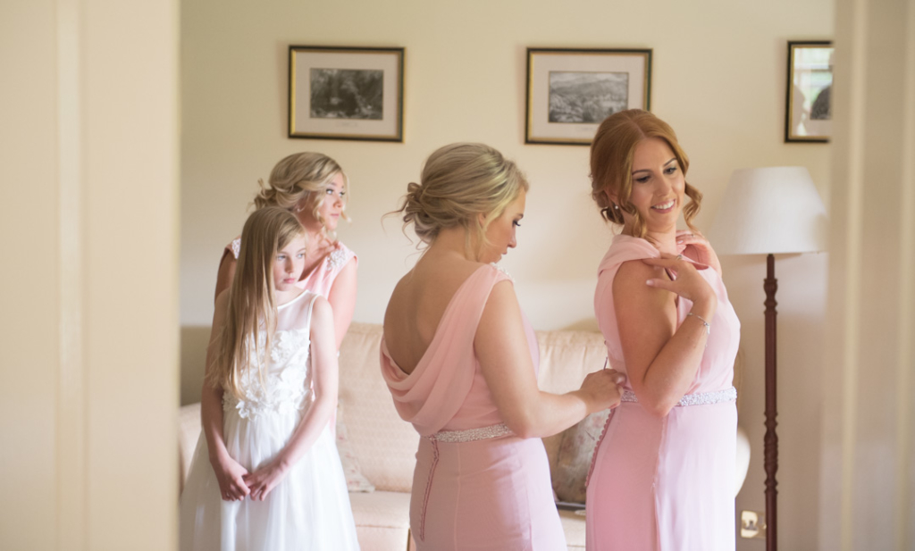 Bridesmaid tying up bridesmaids pink dress