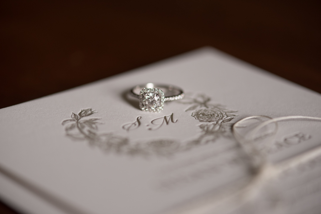 Brides solitaire diamond engagement ring on wedding invite