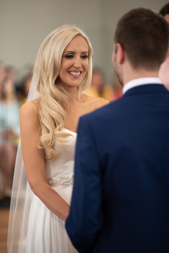 Bride smiling looking at groom at the top of the aisle