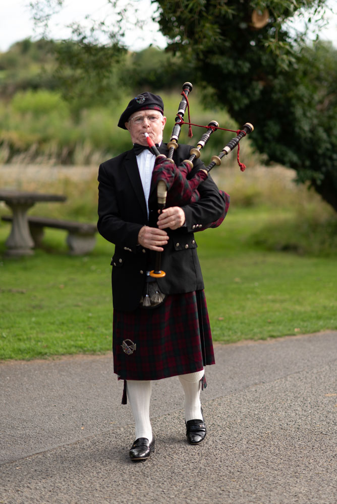 Man in kilt playing the bag pipes on the grounds of the K Club