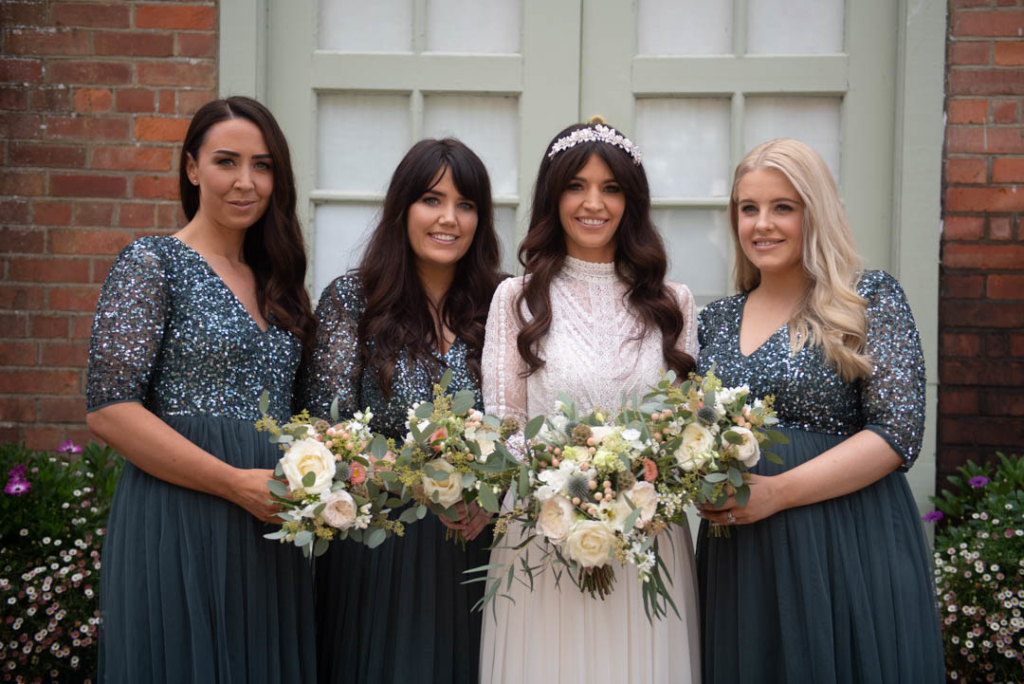 Bride in white and the bridesmaids in green dresses holding their flower bouquets