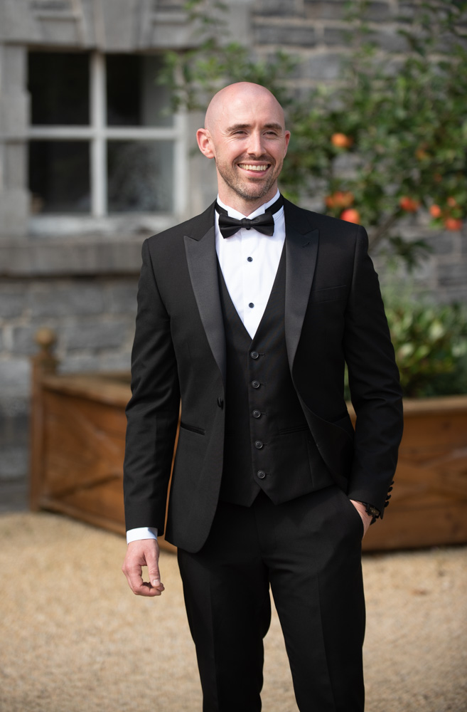 Groom standing in his black three piece suit and black bow tie
