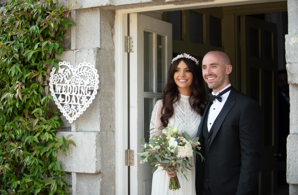 Bride and groom smiling and standing at the doors of the ceremony room at Mill House Slane