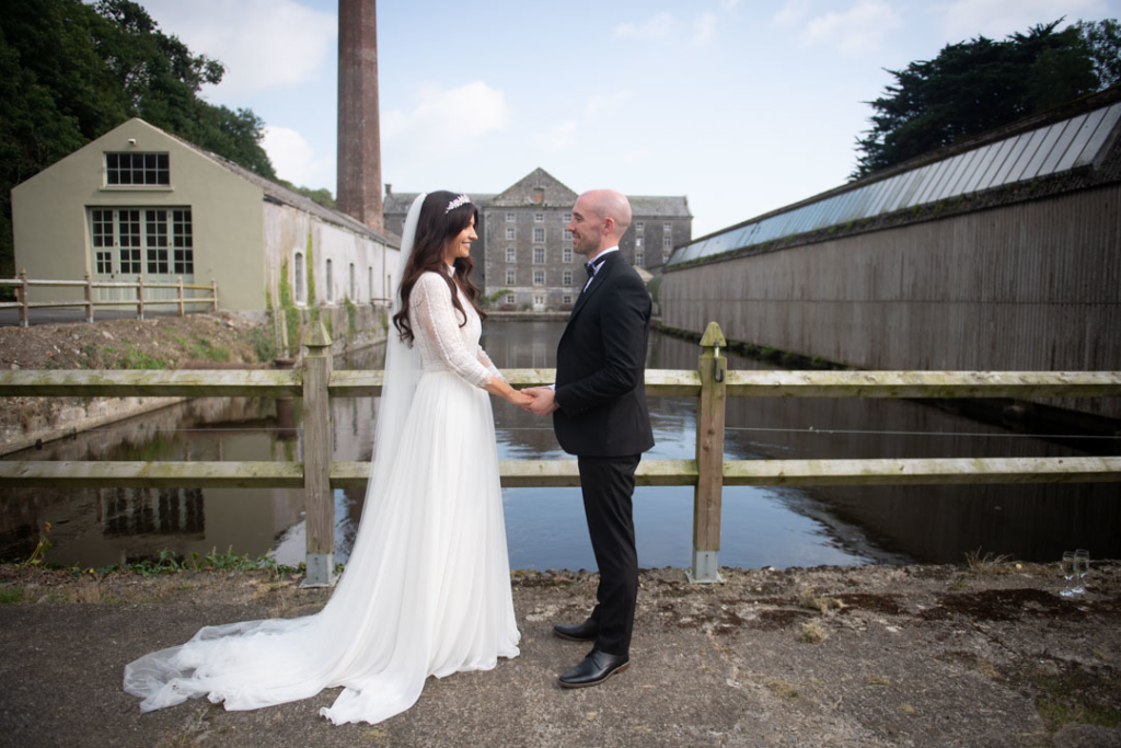 Bride and groom facing each other while holding hands standing in front of the Mill House Slane