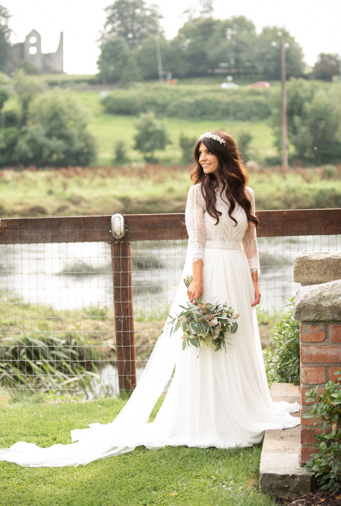 Bride standing in front of the Boyne river holding her flowers at the Mill House Slane