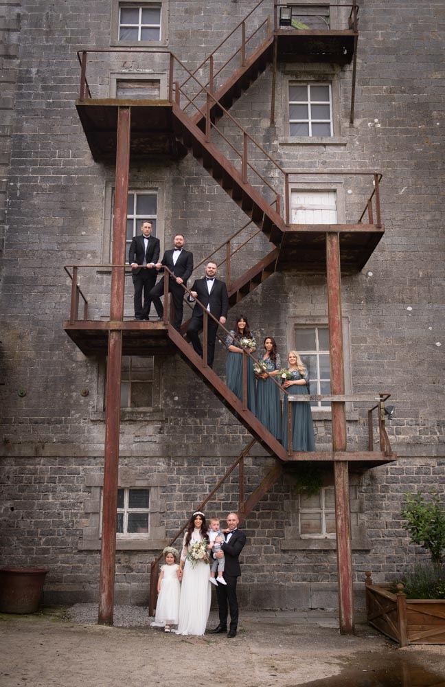 Bride and groom and the bridal party standing on the steps outside the Mill House Slane