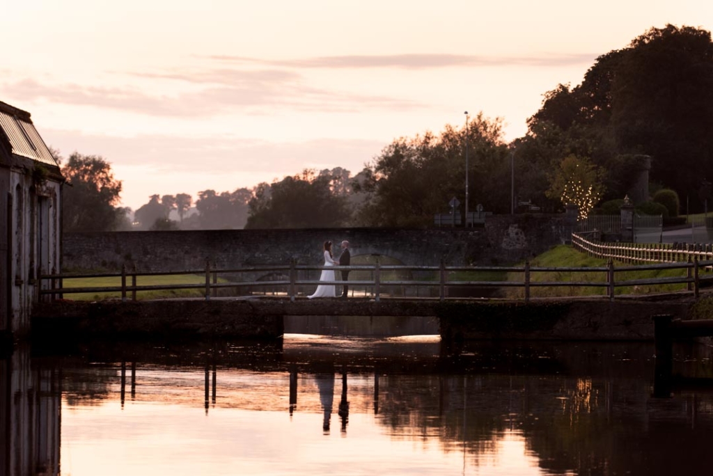 Bride and groom standing on the bridge at the Mill House Slane during sunset