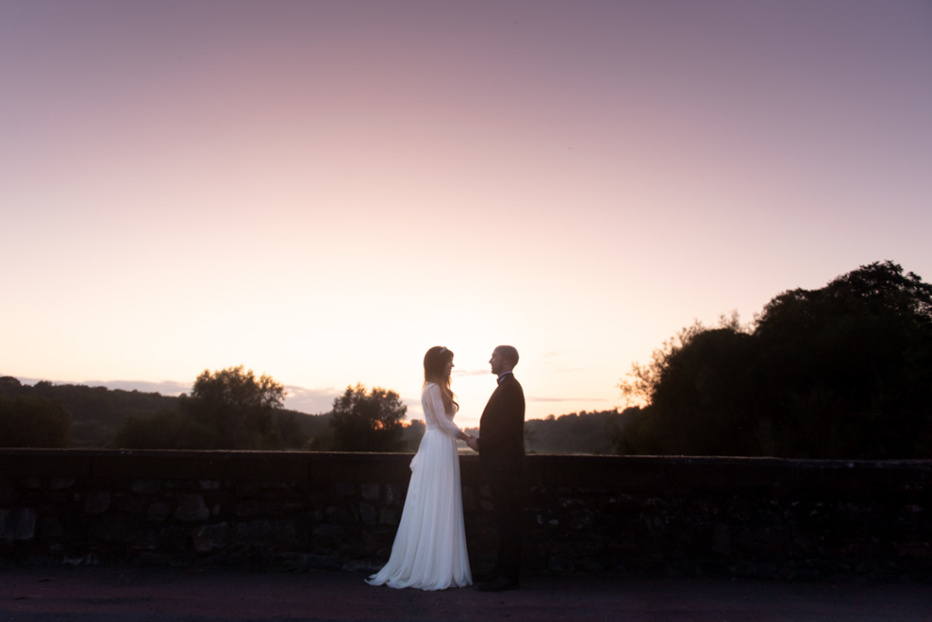 Silhouette of bride and groom with a pink sky behind them