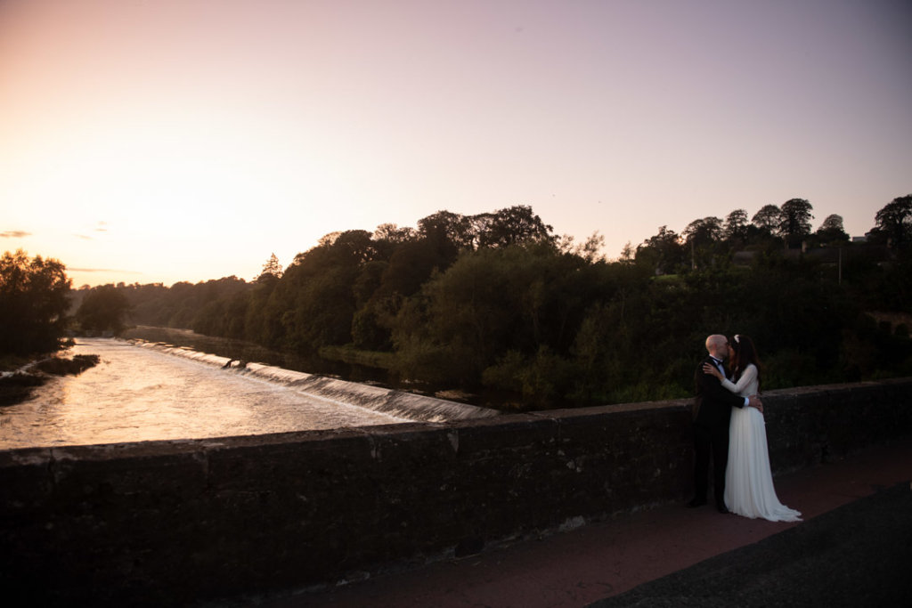 Bride and groom at sunset kissing by the Boyne river at the Mill House Slane