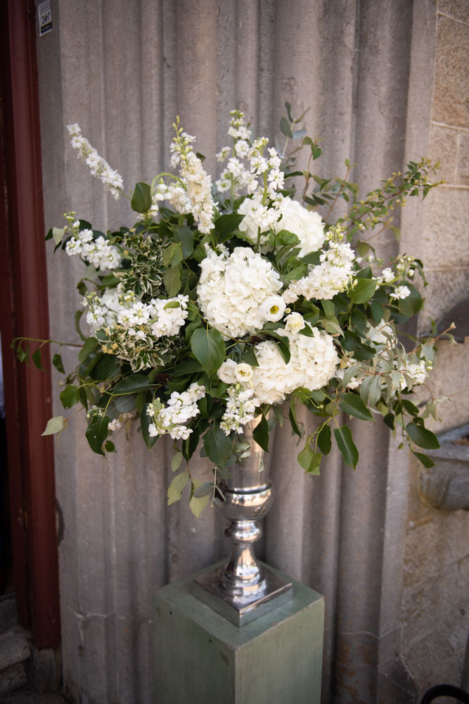 White display of wedding flowers outside either side of the Church doors