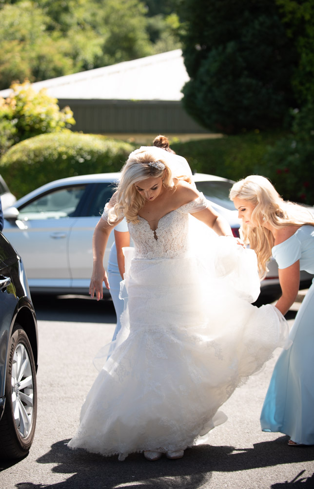 Bridesmaids fixing the Brides wedding dress after getting out of the wedding car