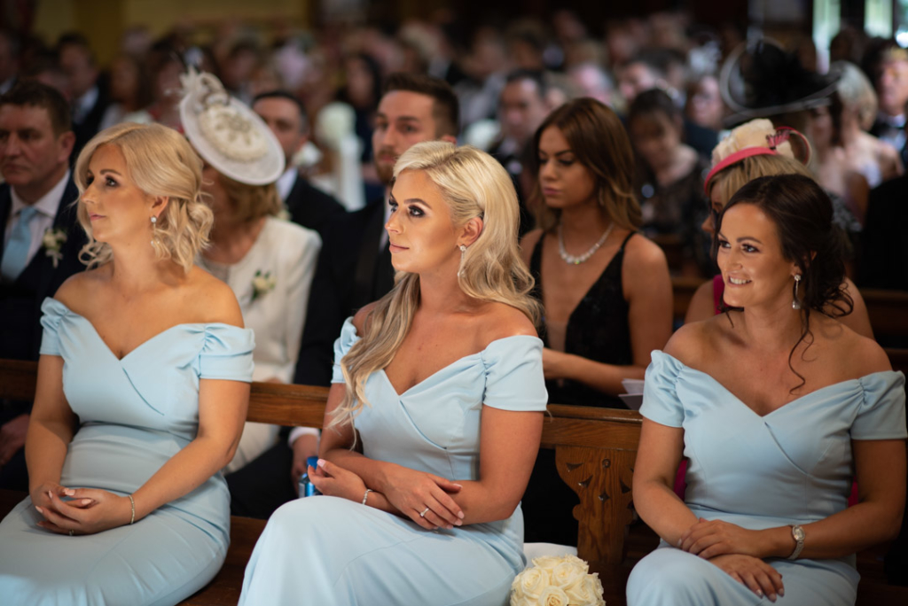 Bridesmaids sitting in the Church in their baby blue dresses