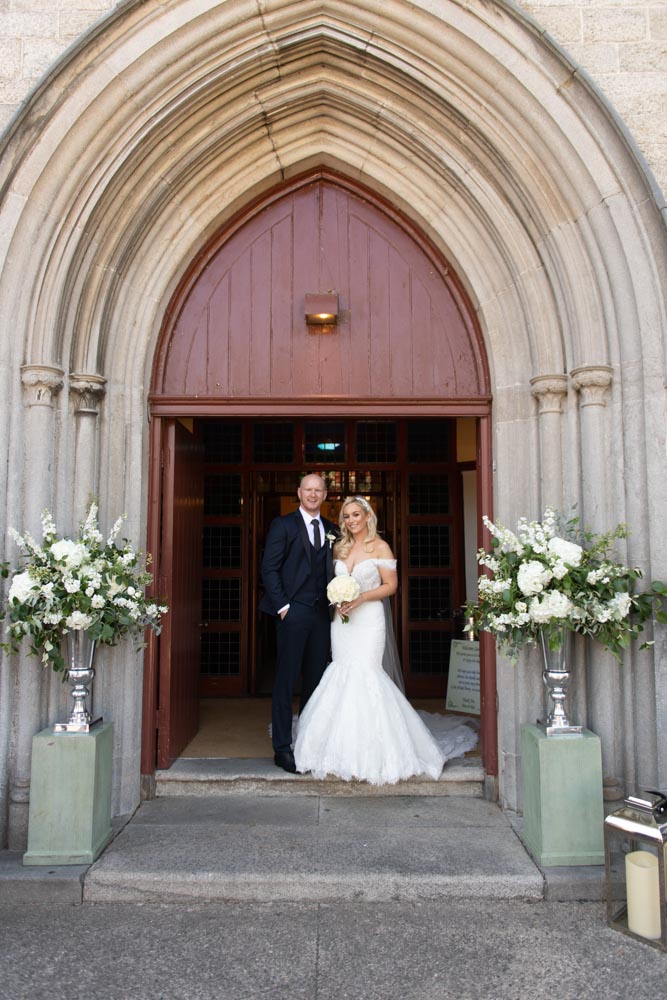 Bride and Groom smiling at the doorway of the Church