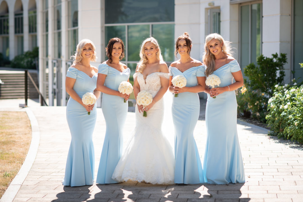 Birde in white and bridesmaids in baby blue dresses standing outside  the Powerscourt Hotel