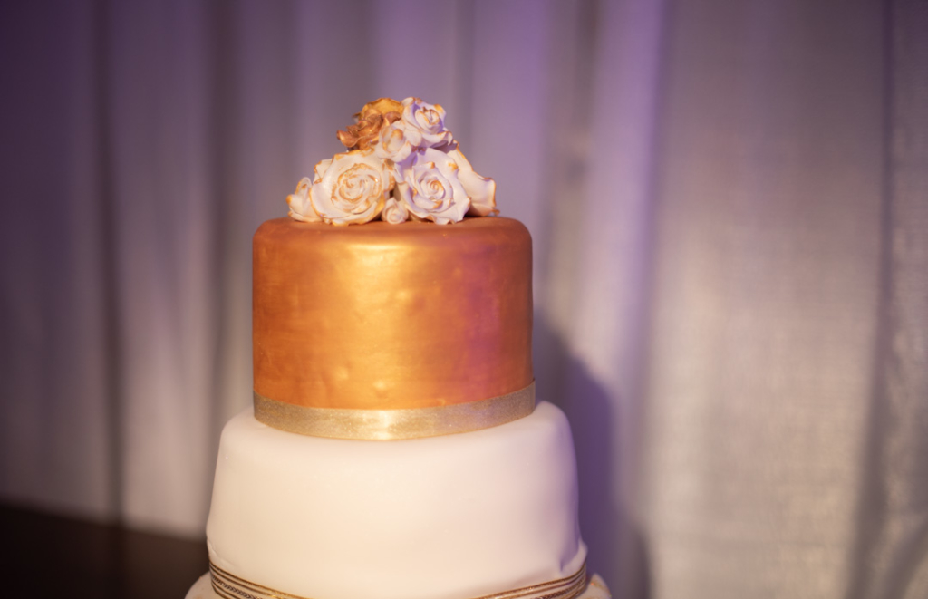 White and gold wedding cake with icing flowers on top