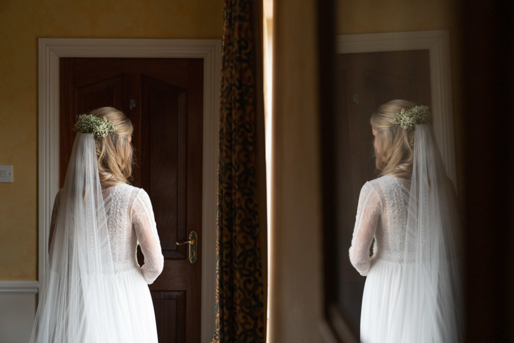 Back of Brides hair and veil and a reflection of her in the mirror