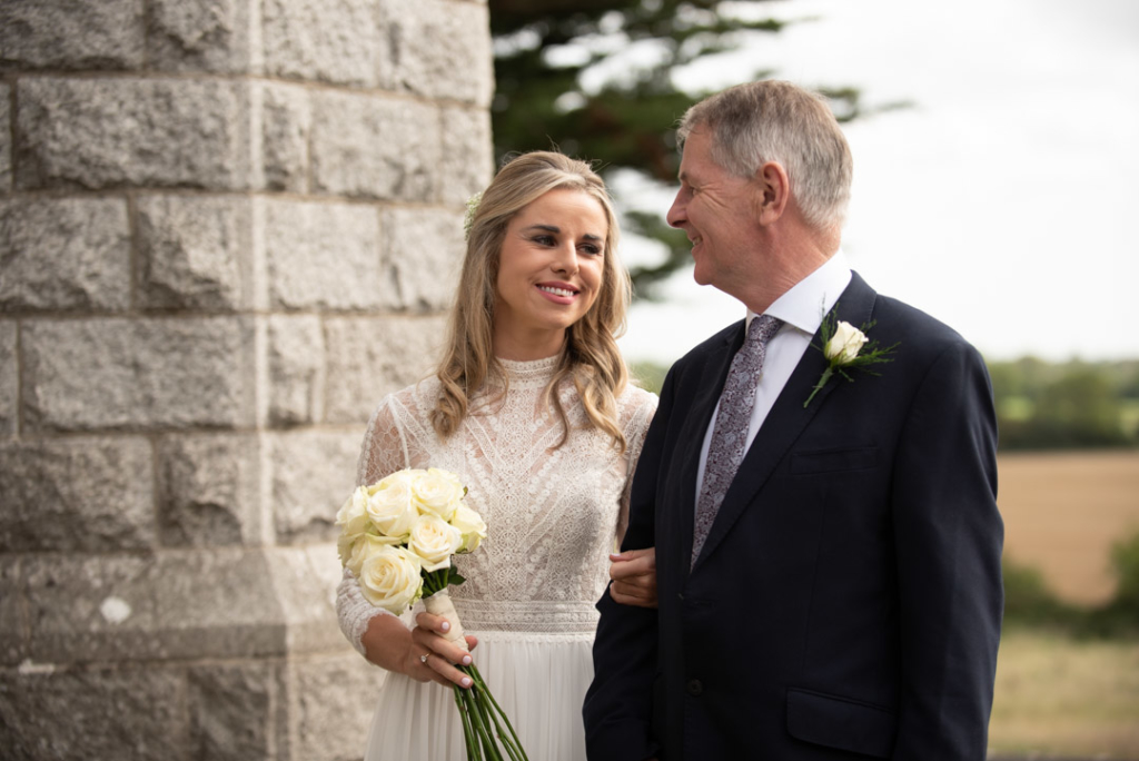 Bride and her dad smiling and looking at each other about to go into the Church to get married