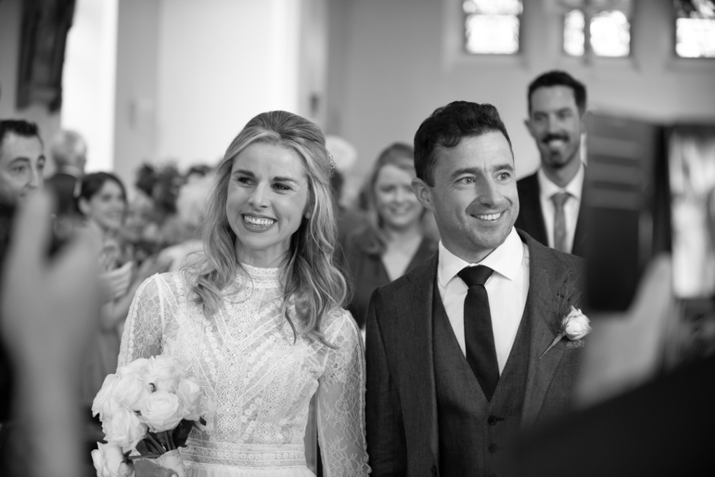 Bride and groom smiling walking down the Church aisle