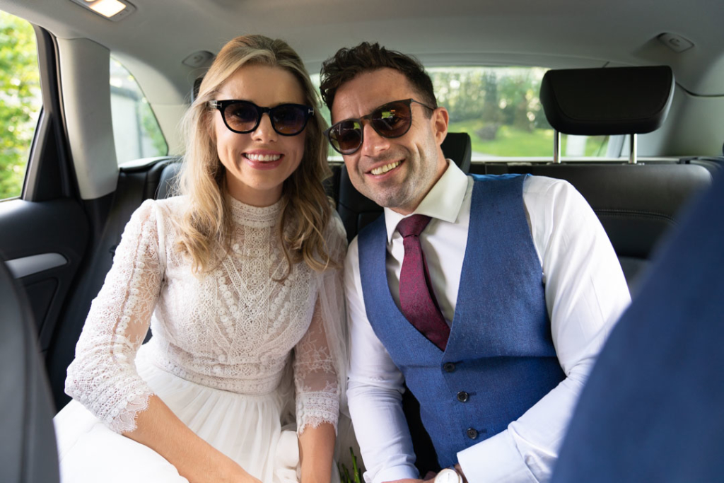 Bride and groom smiling in the back of the wedding car