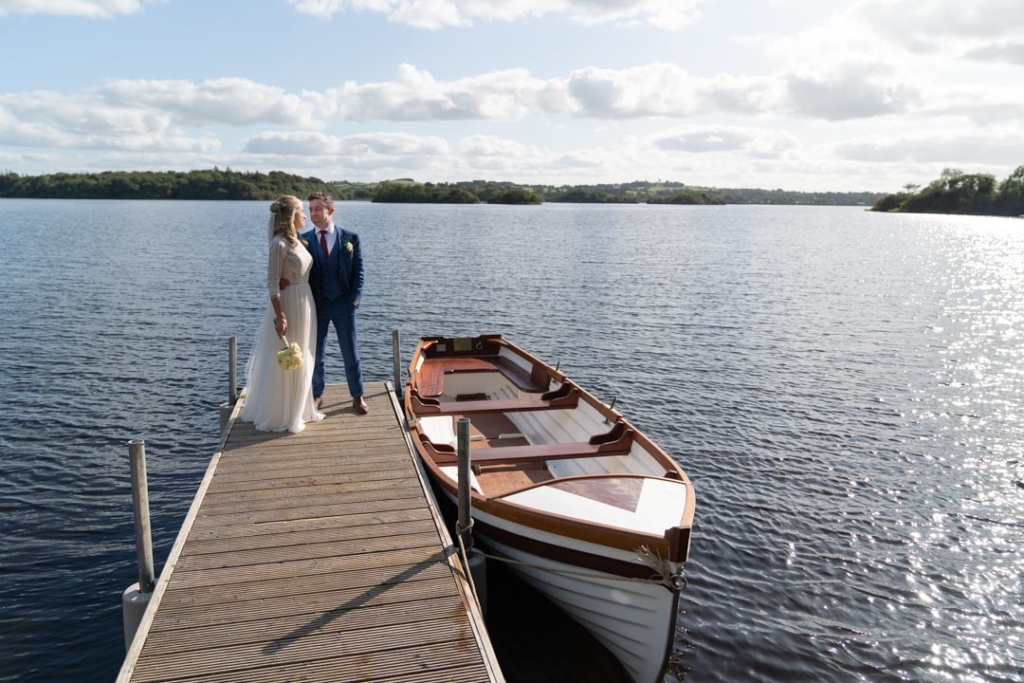 Bride and groom standing on the boardwalk beside the lake and boat at Virginia Park Lodge