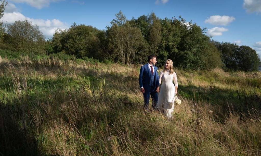 Bride and groom walking through the long grass at their Virginia Park Lodge wedding