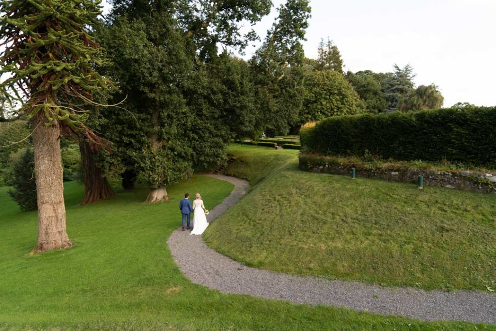 Bride and groom walking in the grounds of Virginia Park Lodge surrounded by big trees