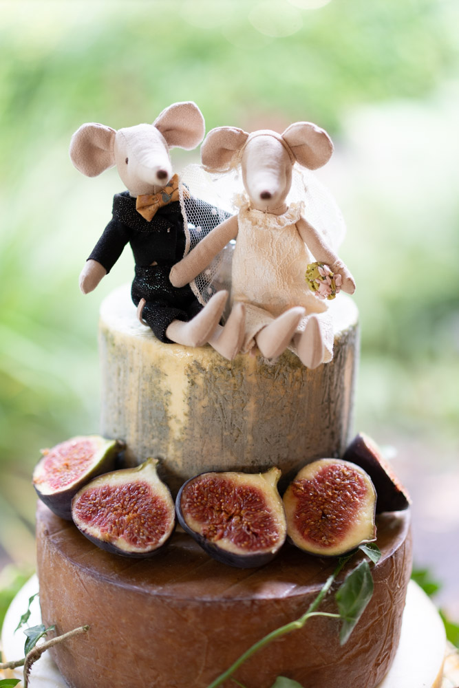 The cake topper of two mice figures sitting on top of the wedding cheese cake