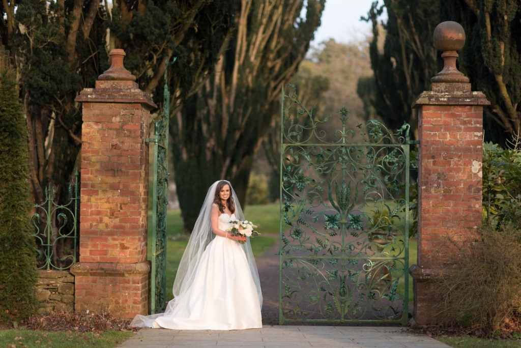 Bride standing in front of the green gates in the gardens of the Tankardstown House wedding venue 