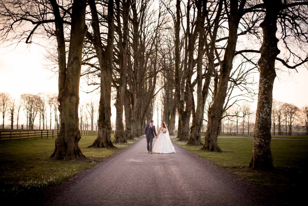 Bride and Groom holding hands while walking down the driveway at Tankardstown House